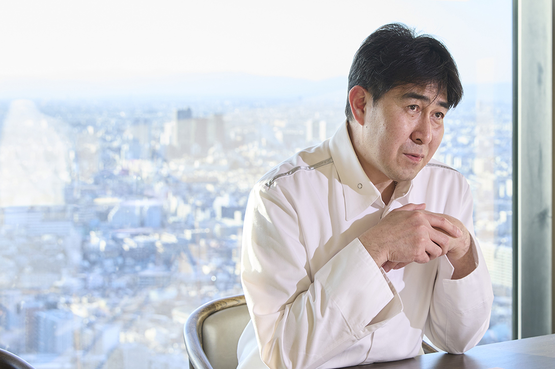新宿の眺望を背景に語る料理長 安保